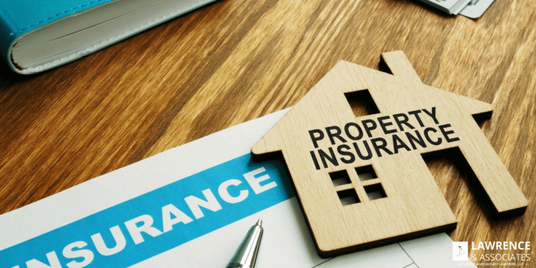 Property insurance paperwork on desk with wooden house on top of it