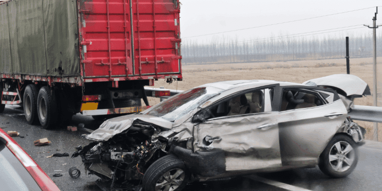 Aftermath of car accident and a truck where the front of the car is shown to have damage