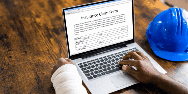 Employee with their left arm in a cast filling out insurance form on laptop