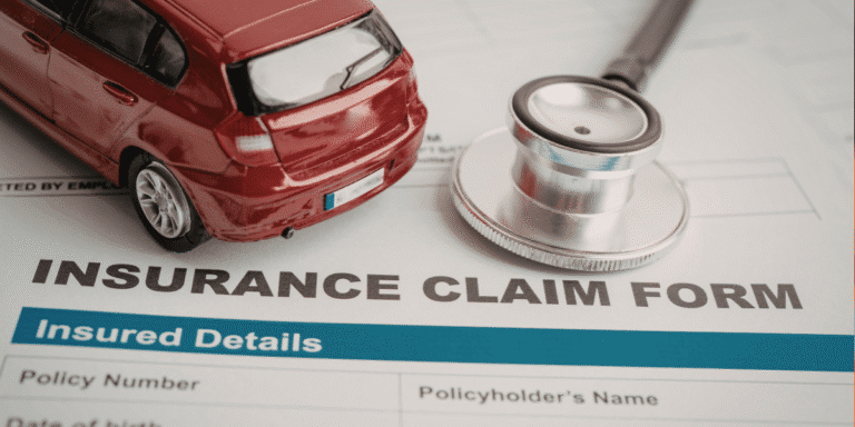 Close up of insurance claim form with toy car and magnifying glass on top of it