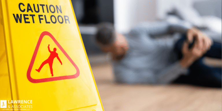 Close up of wet floor sign on the left and a person in the background clutching their leg